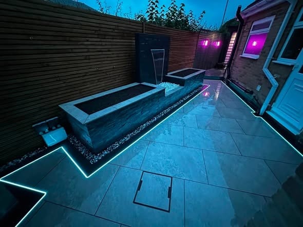 A porcelain garden at night lit with blue LED lights and a water feature